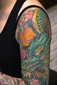 obojeni uzorak tetovaže zmaja koji pokriva cvjetnu ruku