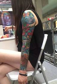 Langhåret pige med tatoveringer med blomsterarme tatoveringer
