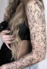 Black gray flower arm tattoo on the woman's arm