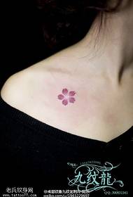 small plum tattoo at the clavicle