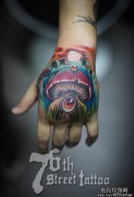 Um padrão de tatuagem de cogumelo de olhos longos na parte de trás da mão
