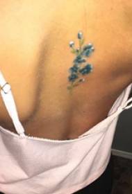 getatoeëerd meisje op de achterkant van de gekleurde kleine verse bloem tattoo foto