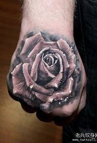 a classic black and gray rose tattoo pattern on the back of the hand