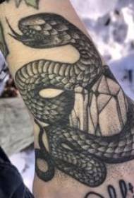 Tatuointi käärmekuvio uroskäden takana mustalla tatuointikäärmekuviolla