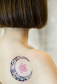 短い髪の女の子の背中の格好良い月と花びらの入れ墨のタトゥー