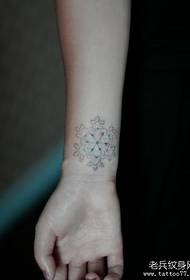a white snowflake tattoo pattern on the wrist of a girl