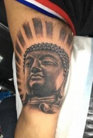 Tattoo foto e një figure të tatuazhuar të një statuje të Budës me një gri të zezë në krah mashkull