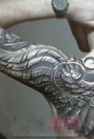 Το χέρι του αγοριού σε μαύρο σκίτσο δημιουργικό φτερό κυριαρχεί η εικόνα τατουάζ λουλουδιών βραχίονα