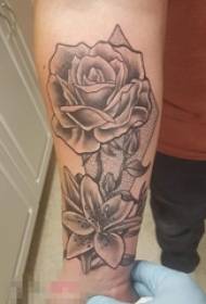 Brațul băiatului pe poza tatuajului cu flori înțepături negre