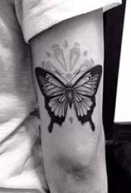 Brazo del niño en la imagen de tatuaje de mariposa de animal pequeño realista negro