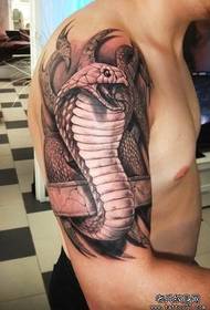 büyük kolundaki bir kobra dövmesi