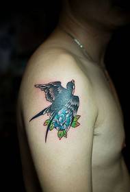 Imagem de tatuagem de uma pequena andorinha colhendo flor no braço grande