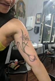 Puška ruku djevojke s uzorkom tetovaže od narcisa na crnoj sivoj slici tetovaža narcis