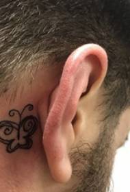 татуіраваны за вухам мужчынскі хлопчык за выявай татуіроўкі чорнай матылькі