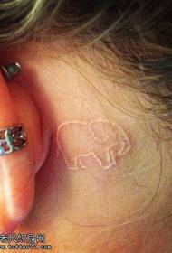 kobiece ucho za białym niewidocznym obrazkiem tatuażu słoniątka