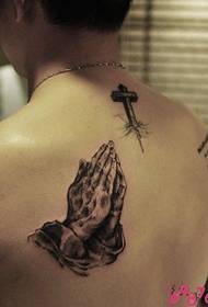 mans nas costas rezando unha foto de tatuaxe cruzada