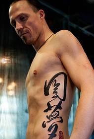uzkrītošs ķīniešu tetovējums vīrieša vidukļa pusē