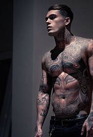 zahraničná pohľadná mužská hviezda plná tetovania s príveskom totem plus bodov