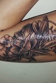 Tatuaj rafinat de flori negre și gri pe interiorul brațului mare