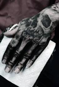 Grillerige swart en wit skedel skelet tattoo op die agterkant van die hand