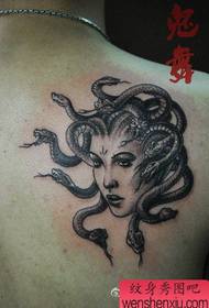 Jongen mei in swartgrize Medusa-tatoet op it skouder