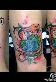 ένα φίδι και ένα μοτίβο τατουάζ αυξήθηκε στο πόδι του κοριτσιού
