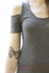 အနက်ရောင်မီးခိုးရောင်ပွိုင့်ပေါ်တွင်မိန်းကလေး၏လက်မောင်းသည်ရိုးရှင်းသောမျဉ်းသေးငယ်သည့်တိရိစ္ဆာန်လိပ်ပြာပုံ tattoo ရုပ်ပုံလွှာဖြစ်သည်
