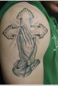 braç misteriós patró de tatuatge de creu que brilla amb mans orant