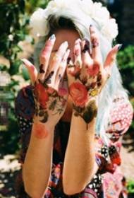 မိန်းကလေးသည်လက်၏နောက်ကျောတွင်ဆေးခြယ်ထားသော gradient letterary ပန်း tattoo ရုပ်ပုံကိုခြယ်သထားသည်