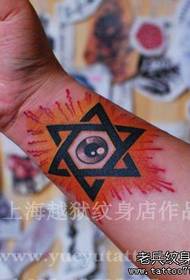 Berniuko rankos su šešiabriauniu žvaigždės ir akių tatuiruotės piešiniu