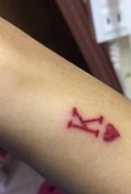 男の子の腕に赤い幾何学的なラインハートと手紙のタトゥーの写真