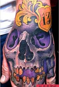 a purple skull tattoo on the back of the hand