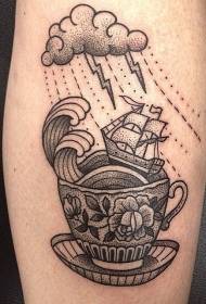 černý vztyčený šálek čaje s tetováním plachetnice