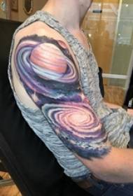 男生手臂上彩绘渐变抽象线条宇宙和星球纹身图片