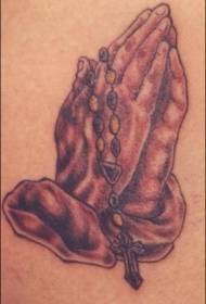 Bàn tay cầu nguyện cổ điển với hình xăm chữ thập