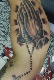 braç de pregària a mà i imatge de tatuatge de rosari