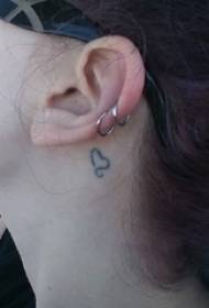 耳の後ろの女の子の黒い線のハート型の小さなパターンの文学的なタトゥーの写真
