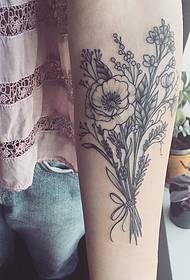 krahu i vajzës në aranzhimin delikate të luleve të bimëve. Tattoo.
