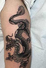 hand on the arm of the beautiful black dragon pattern tattoo