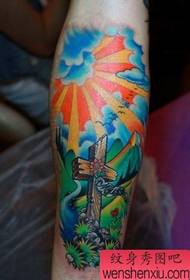 een kleurrijk gekleurd kruis tattoo-patroon op de arm