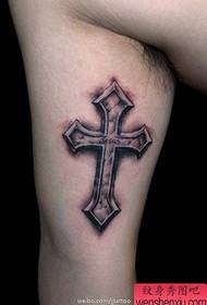 Braç masculí dins de patrons clàssics de tatuatge de creu