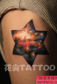 Braço com uma estrela de seis pontas e um padrão de tatuagem estrelado