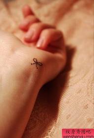 small and popular bow tattoo pattern on the wrist of the girl